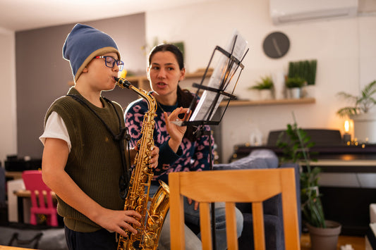Boy playing saxophone with teacher instructing