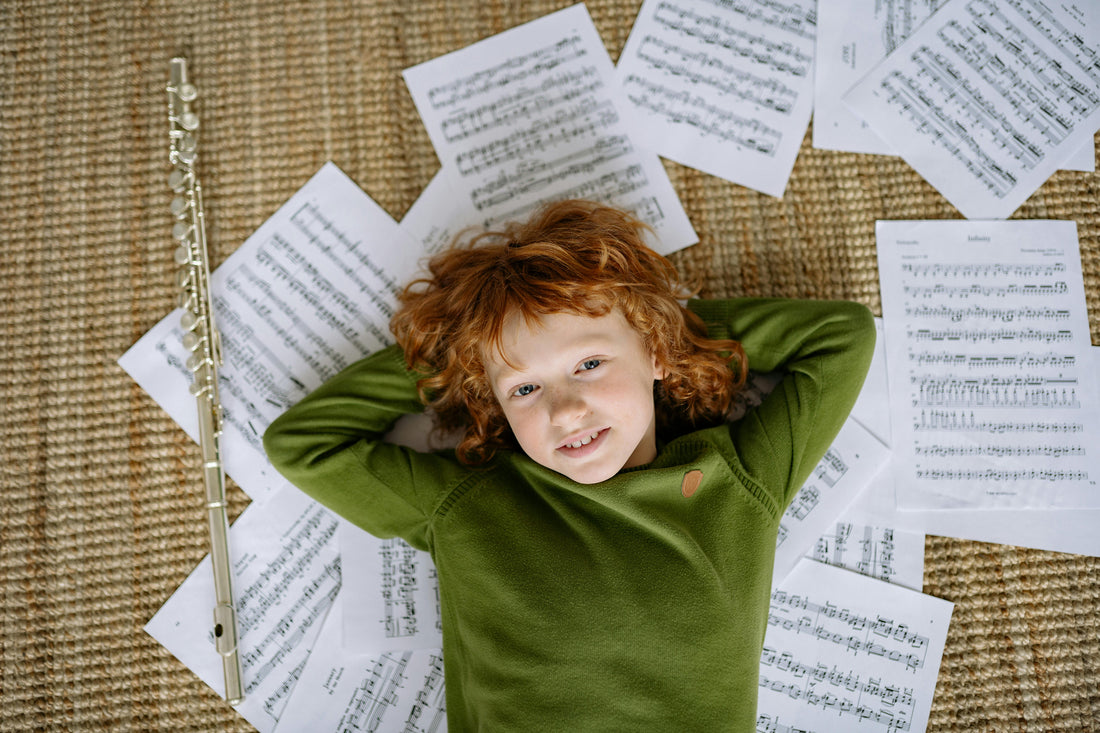 boy laying on floor next to flute and sheet music