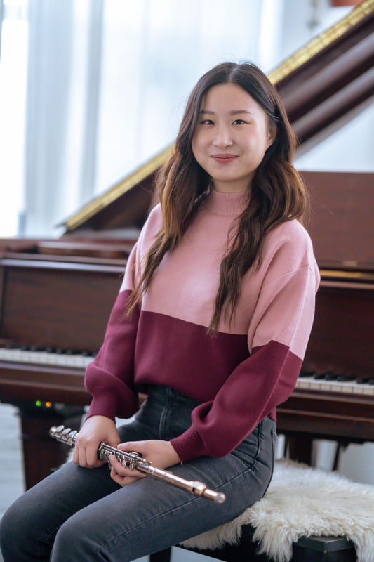 Teen Girl sitting in front of piano with a flute on her lap
