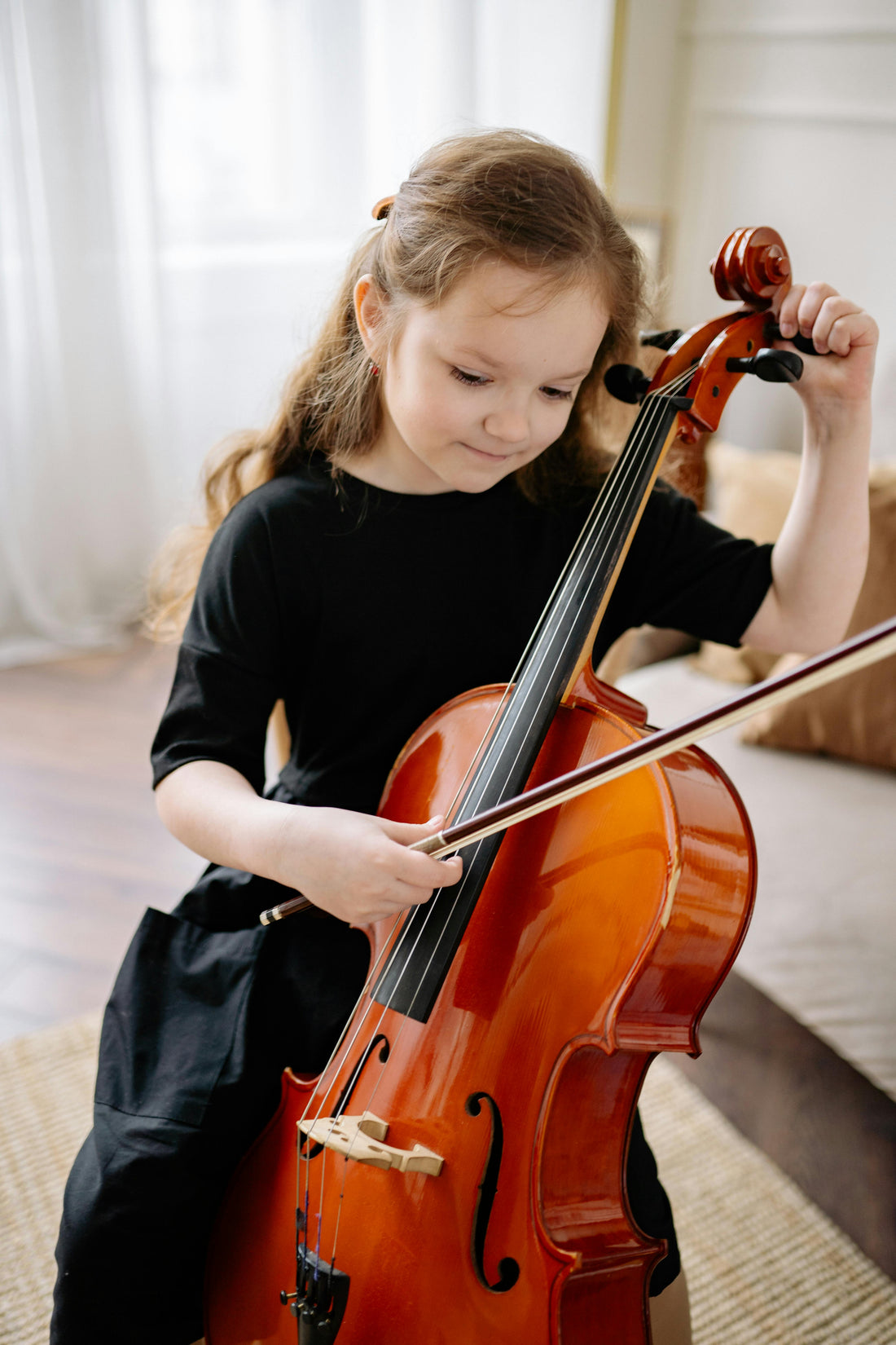 small girl tuning a cello