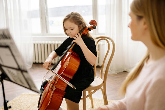 Girl playing cello alone with an adult watching