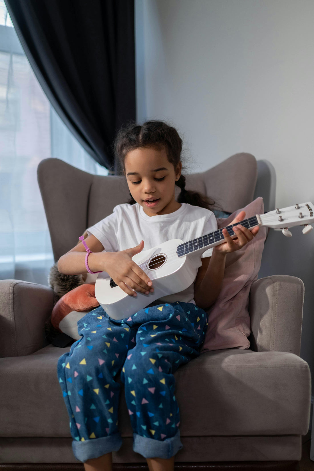 Girl sitting while playing ukulele and singing
