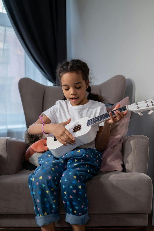 Girl sitting while playing ukulele and singing