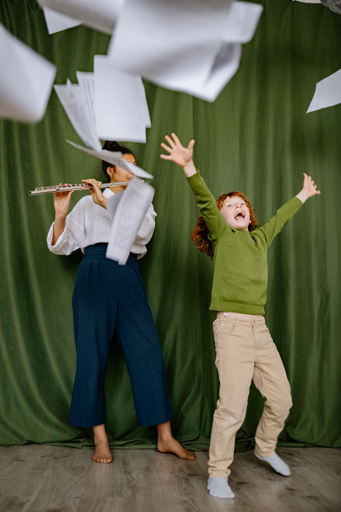 Boy throwing sheet music with adult playing flute