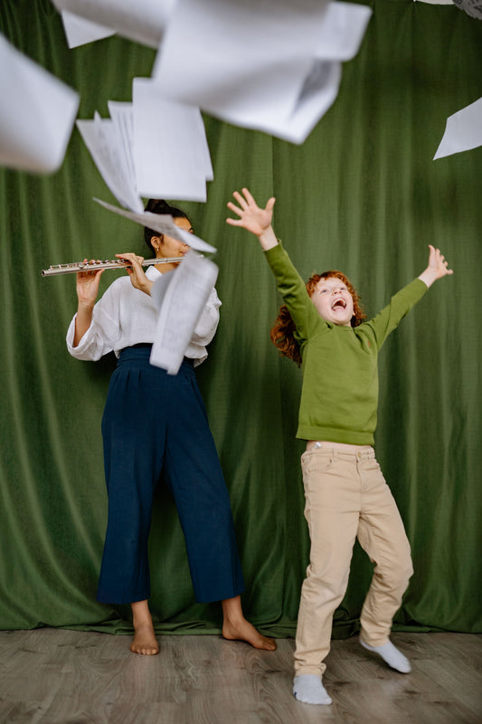 Boy throwing sheet music with adult playing flute