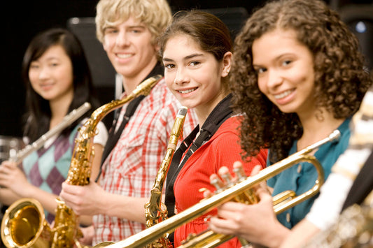 four kids smiling with band instruments