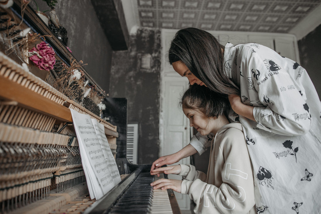 Mom helping Girl learn piano