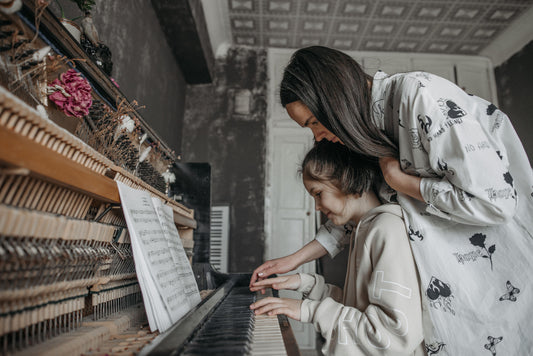 Mom helping Girl learn piano