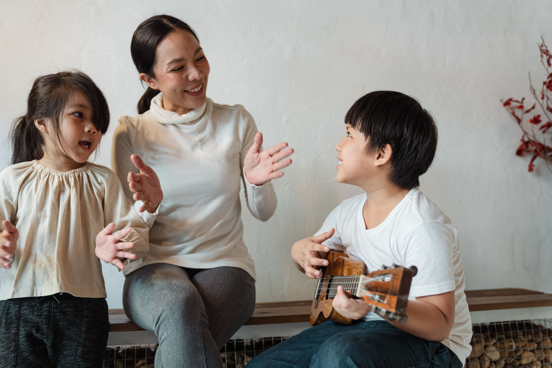 family clapping with young boy playing ukulele