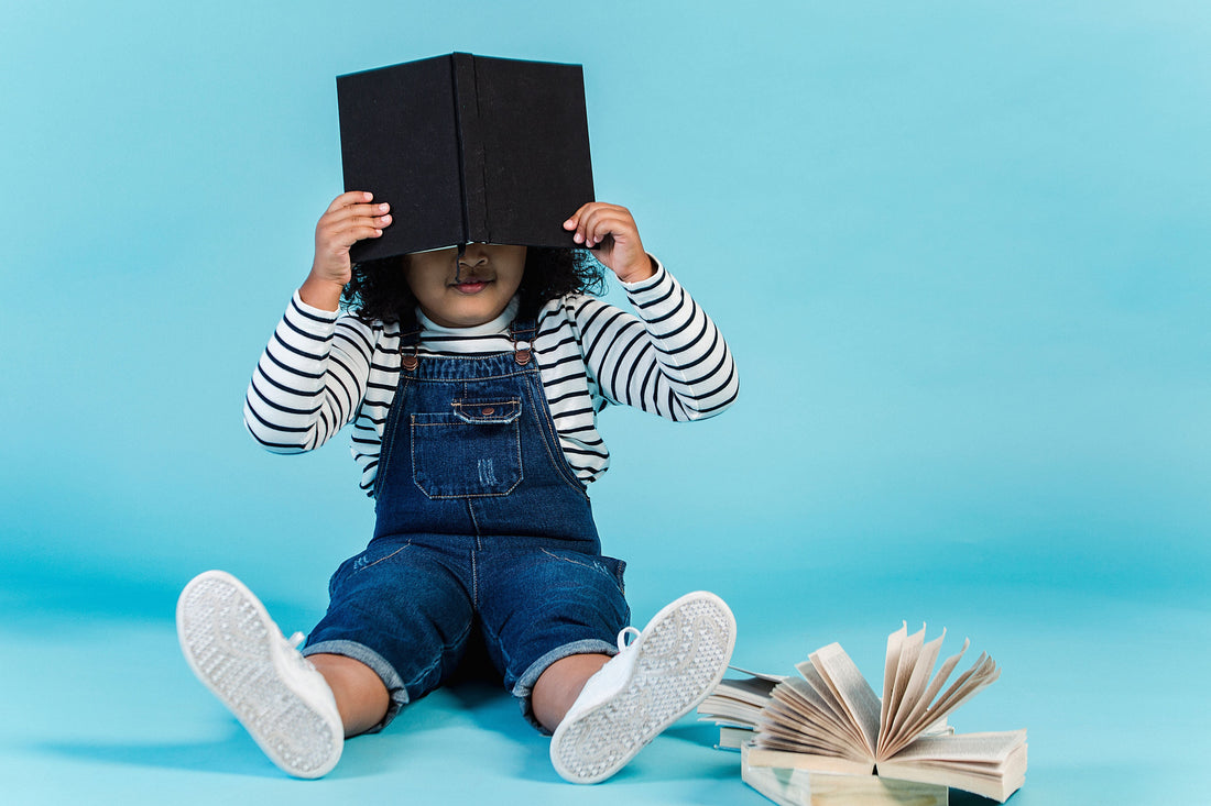 shy child hiding behind book