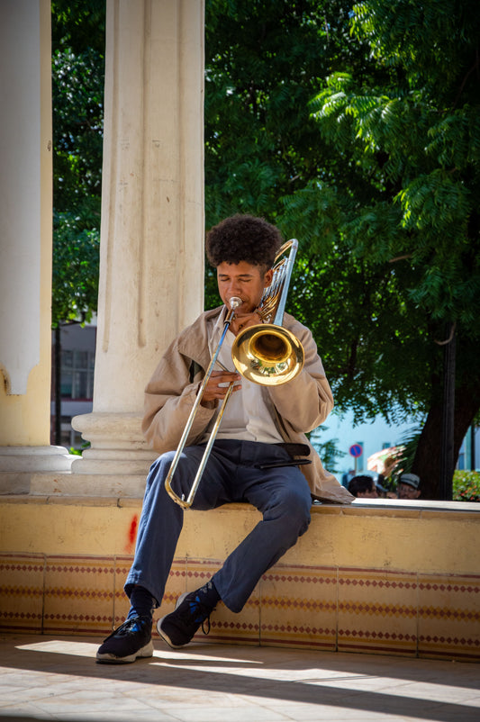 Teen sitting playing on trombone